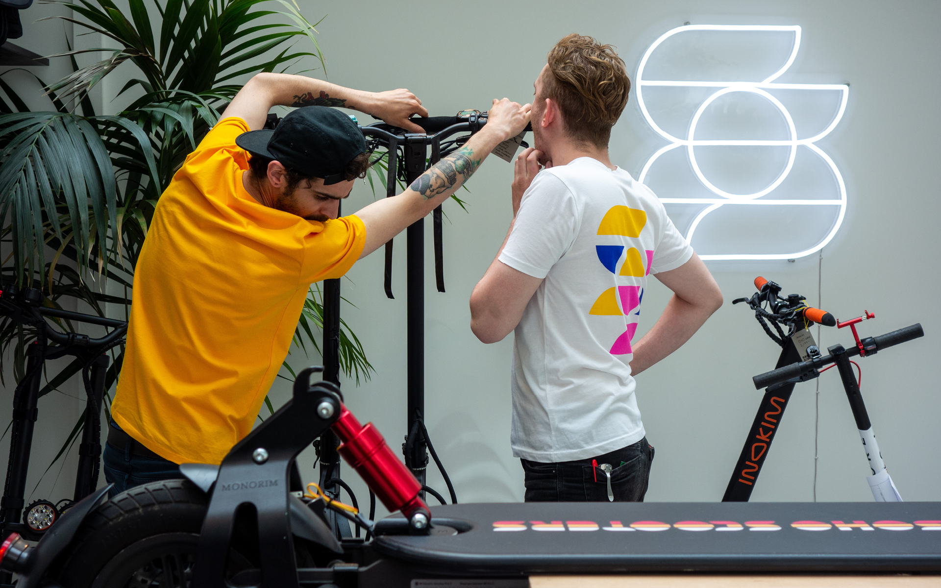 Soho Scooters engineers displaying branded merchandise and workshop